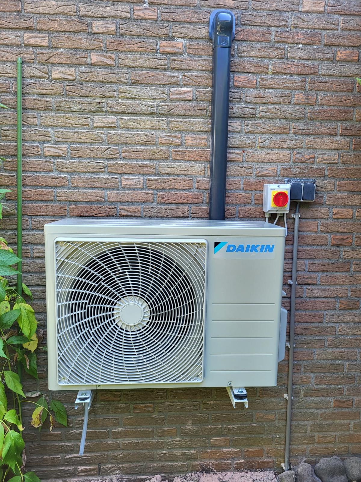 Daikin buitenunit gemonteerd aan een steenachtige gevel
